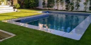 Modern backyard swimming pool surrounded by synthetic grass, offering a clean, low-maintenance outdoor design solution.