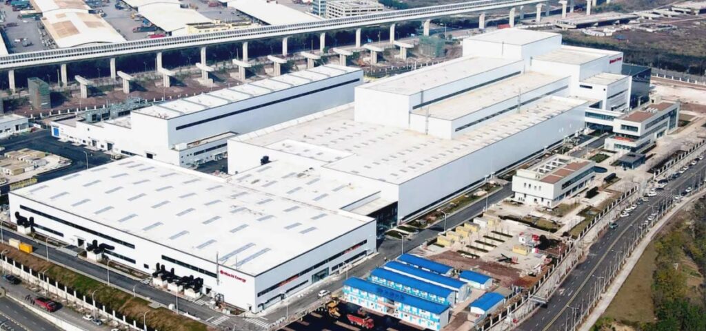 Aerial view of a modern manufacturing factory in China with warehouse buildings and logistics infrastructure.